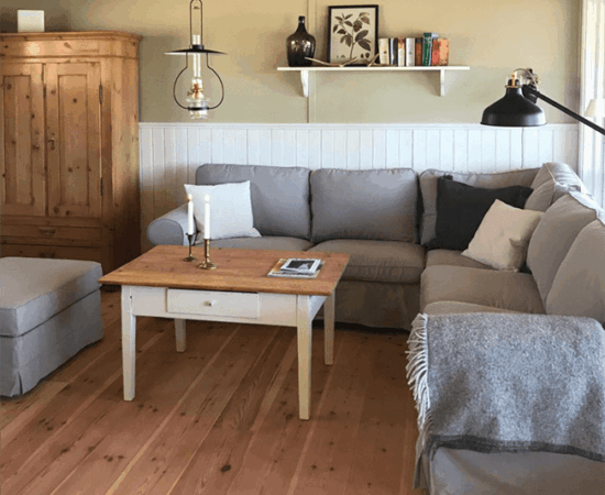 Das Wohnzimmer mit Couch, Tisch und Schrank und Holzdielen